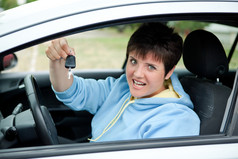 快乐年轻的女人显示的关键她的新车她的手的路