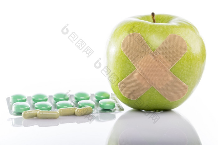 绿色苹果与邦迪牌创可贴而且一些药片绿色苹果与邦迪牌创可贴而且一些药片白色背景