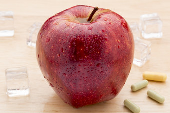 色彩斑斓的医学胶囊和红色的苹果色彩斑斓的医学胶囊和红色的苹果木背景