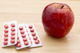 红色的药片泡包和红色的苹果红色的药片泡包和红色的苹果木背景