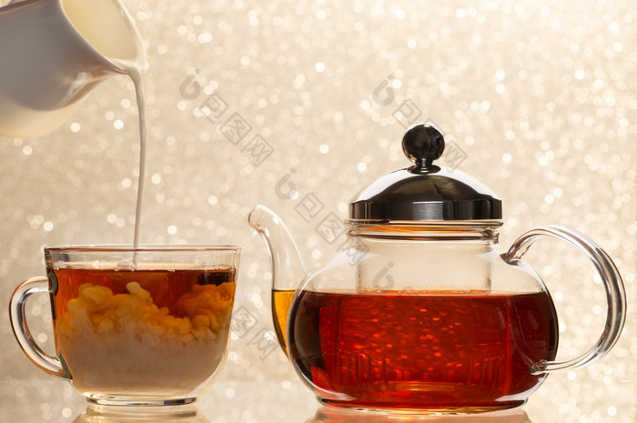 溶解牛奶杯黑色的茶透明的茶壶和杯溶解牛奶杯黑色的茶透明的茶壶和杯模糊背景