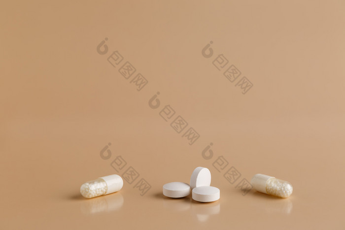 各种各样的白色药片和胶囊各种各样的白色药片米色背景