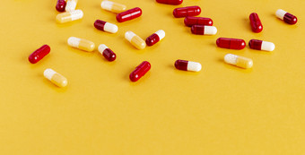 分散黄色的和红色的药物胶囊与活跃的微粒黄色的背景分散黄色的和红色的药物胶囊与活跃的微粒