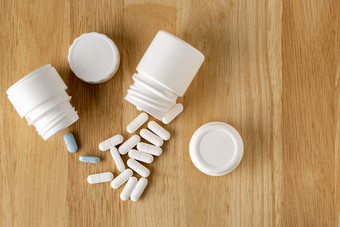 医疗设置塑料白色和玻璃瓶药用蓝色的和白色药片木表格医疗设置塑料白色和玻璃瓶药用蓝色的和白色药片