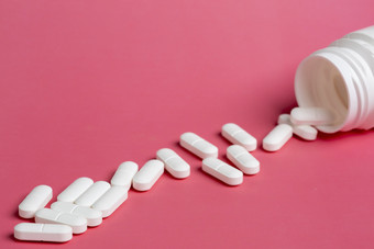 三个玻璃瓶药片粉红色的背景分散白色药物塑料白色瓶药片粉红色的背景分散白色药片