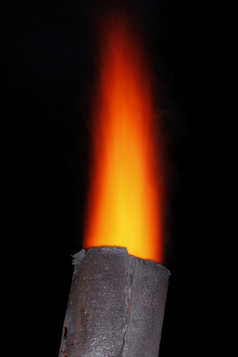 红色的火炬火焰在的老金属烟囱晚上