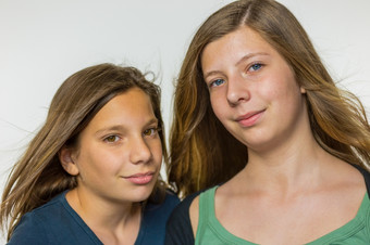 肖像两个高加索人十几岁的女孩与长吹头发孤立的白色背景