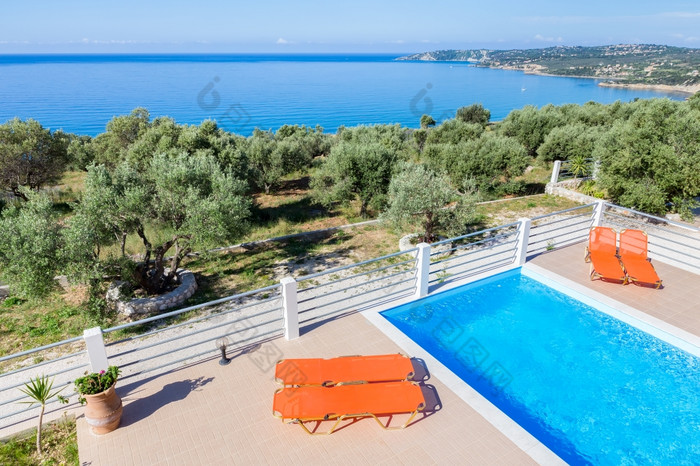 躺椅阳台与蓝色的游泳池附近海海岸希腊