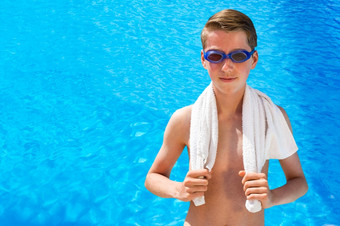 欧洲十几岁的男孩穿游泳护目镜而且白色毛巾蓝色的游泳池