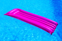 粉红色的空气床垫浮动水蓝色的游泳池