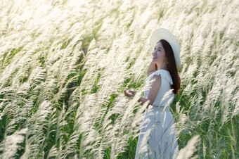 美丽的亚洲女人自然白色草地花她的衣服和白色他站白色长满草的场巴蜀府基里汗泰国美丽的女人自然白色草地花