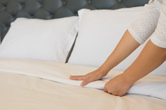 年轻的酒店女仆准备的清洁房间的酒店与清洁白色毯子的床上和枕头的卧室的早....软毛巾卧室
