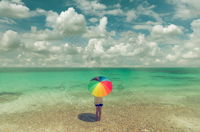 亚洲女人和色彩斑斓的雨伞站的海滩蓝色的天空女人和色彩斑斓的雨伞