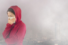 女人与流感打喷嚏女人穿着粉红色的冬天服装穿面具她的鼻子冷和流感健康概念对有毒灰尘覆盖的城市曼谷有健康效果曼谷空气污染