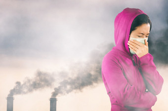 女人与流感打喷嚏女人穿着粉红色的冬天服装穿面具她的鼻子冷和流感健康概念对空气污染背景空气污染