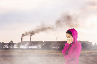 女人与流感打喷嚏女人穿着粉红色的冬天服装穿面具她的鼻子冷和流感健康概念对空气污染背景空气污染