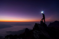 轮廓登山者背包客他的手举行的光高以上他的头站的岩石山峰日落成功赢家领袖概念领袖前