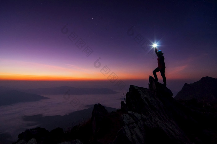 轮廓登山者背包客他的手举行的光高以上他的头站的岩石山峰日落成功赢家领袖概念领袖前