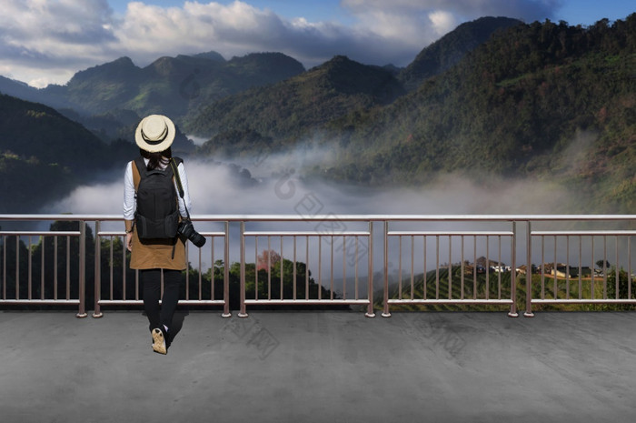 亚洲女游客她穿休闲风格日本与简单的黑色的背包和相机与镜头后面看景观视图秋天亚洲女游客秋天