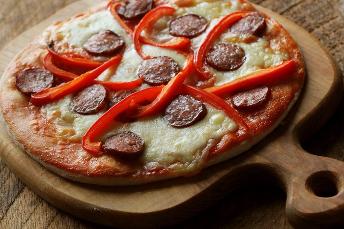 热自制的披萨与意大利辣香肠paprica木表格前视图热自制的披萨与意大利辣香肠paprica木表格前视图