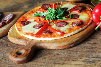 热自制的披萨与意大利辣香肠papricarucola木表格热自制的披萨与意大利辣香肠papricarucola木表格