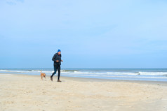 高级男人。与狗运行在一起的海滩