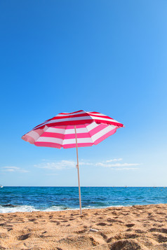 空海滩与波海和条纹粉红色的阳伞