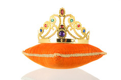 橙色皇家天鹅绒枕头与皇冠孤立的在白色背景
