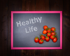 的图片黑板上的左一边与写健康的生活和的正确的一边樱桃番茄木背景