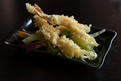 日本厨房天妇罗虾深炸虾与酱汁和蔬菜黑色的板黑色的背景浅深度场