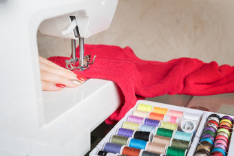 年轻的女人缝纫织物缝纫机缝纫过程的阶段overstitchin彩色的线轴