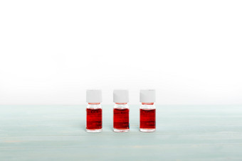三个医学瓶填满与红色的液体安排行白色背景