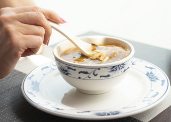 女人吃与陶瓷勺子中国人蔬菜汤的餐厅