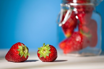 关闭两个<strong>草莓</strong>表格与蓝色的背景和玻璃Jar完整的<strong>草莓</strong>的背景关闭两个<strong>草莓</strong>表格与蓝色的背景