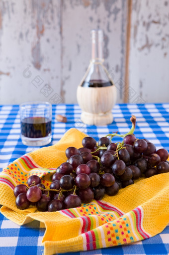 群红色的葡萄和玻璃红色的酒与<strong>酒瓶</strong>背景在网纹桌布群红色的葡萄和玻璃红色的酒与<strong>酒瓶</strong>