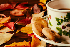 特写镜头杯茶与饼干和秋天的树叶在黑暗表格特写镜头杯茶与饼干和秋天的树叶