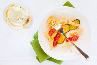 传统的意大利彭意大利面与西葫芦樱桃西红柿和玻璃白色酒见过从以上意大利彭意大利面与西葫芦和樱桃西红柿