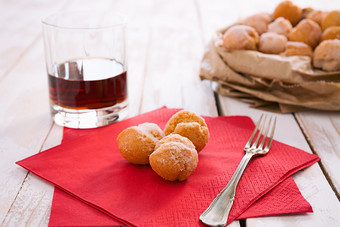 castagnole典型的意大利狂欢节甜蜜的红色的餐巾和玻璃利口酒castagnole典型的意大利狂欢节甜蜜的