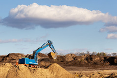 挖掘机沙坑在土方作品的背景的蓝色的天空挖掘机沙坑在土方作品的蓝色的天空