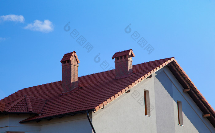 房子与砖烟囱明亮的阳光对深蓝色的天空烟囱的屋顶的房子对的蓝色的天空