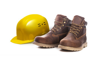 工作安全概念与硬工人黄色的头盔和靴子孤立的白色背景关闭男人。脚踝靴子棕色（的）颜色与牛巴革皮革
