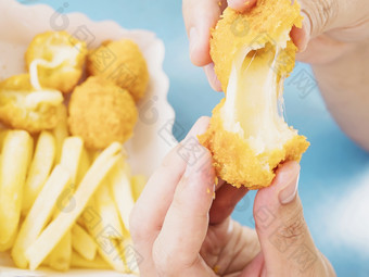 手持有<strong>拉伸</strong>奶酪球准备好了吃与软集中法国薯条蓝色的表格背景