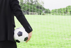 足球团队经理持有球与目标网和绿色草场背景