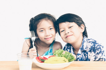 古董风格照片亚洲男孩和女孩是幸福的吃新鲜的蔬菜沙拉与玻璃牛奶孤立的在白色背景
