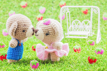 可爱的吻婴儿熊用钩针编织娃娃草与模糊草莓背景