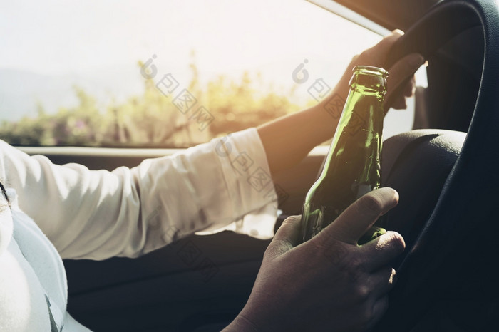 女人持有啤酒瓶而开车车