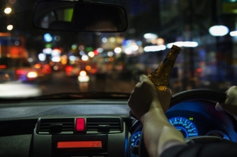 男人。喝啤酒而开车晚上的城市危险的左手开车系统