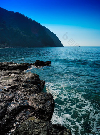 垂直生动的多石的海滩潮汐波与船景观背景垂直生动的多石的海滩潮汐波与船景观引入