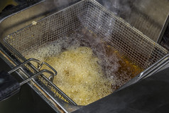 油炸锅为土豆与薯条与沸腾石油概念快食物餐厅厨房设备