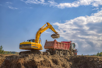 黄色的挖掘机和<strong>空转</strong>储卡车工作的建设网站
